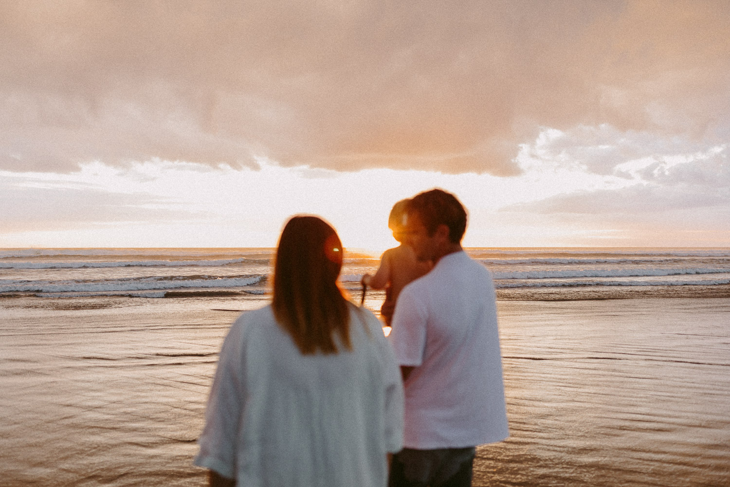 family with little boy at beach at sunset