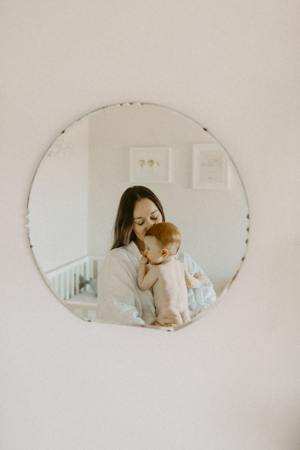 Candid natural photo in mirror of mum holding baby
