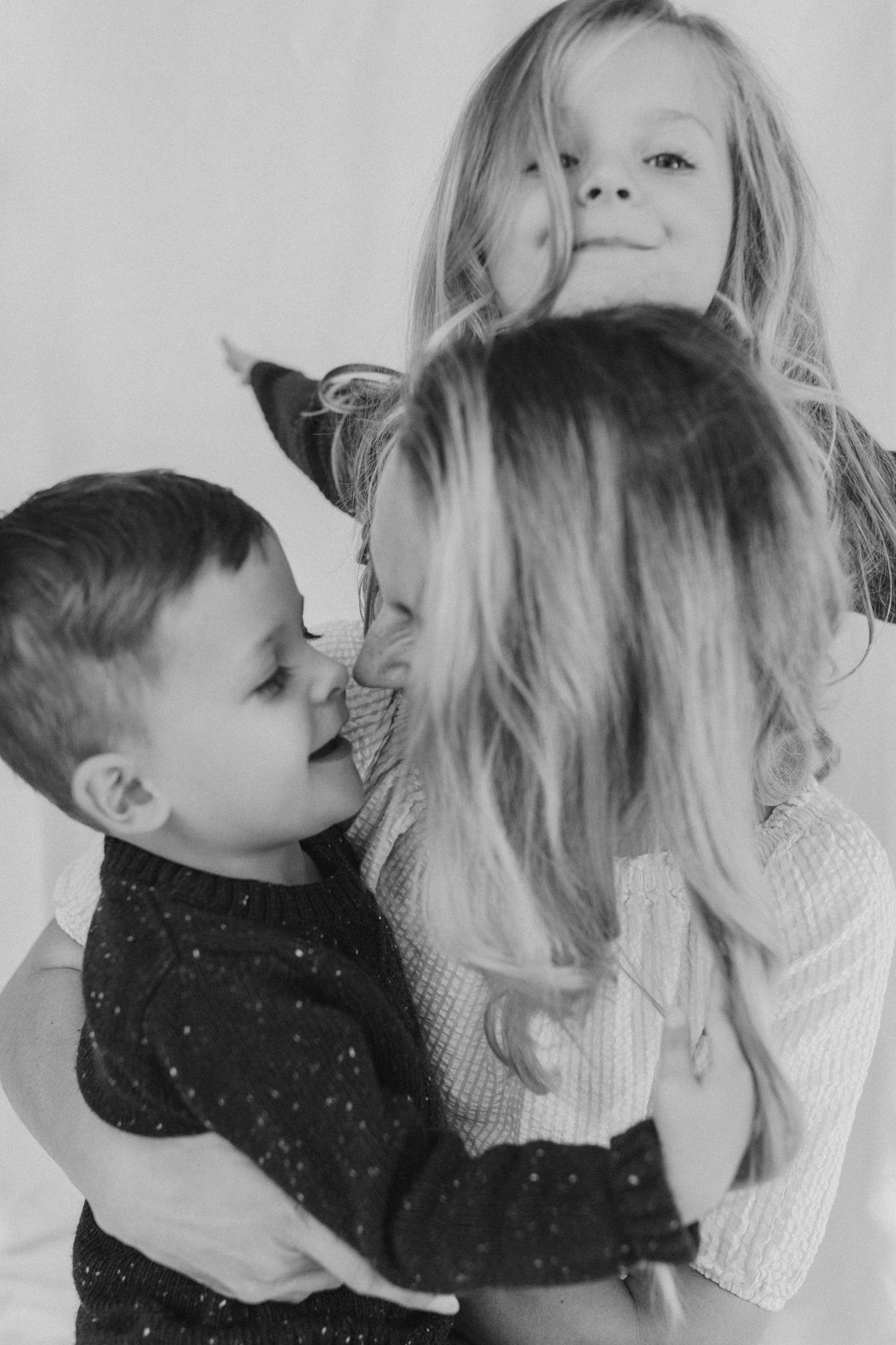 Mum with cuddling her little kids against a white linen backdrop