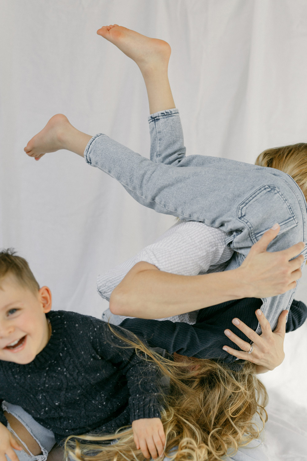 Mum with having fun with 2 young kids against a white linen backdrop