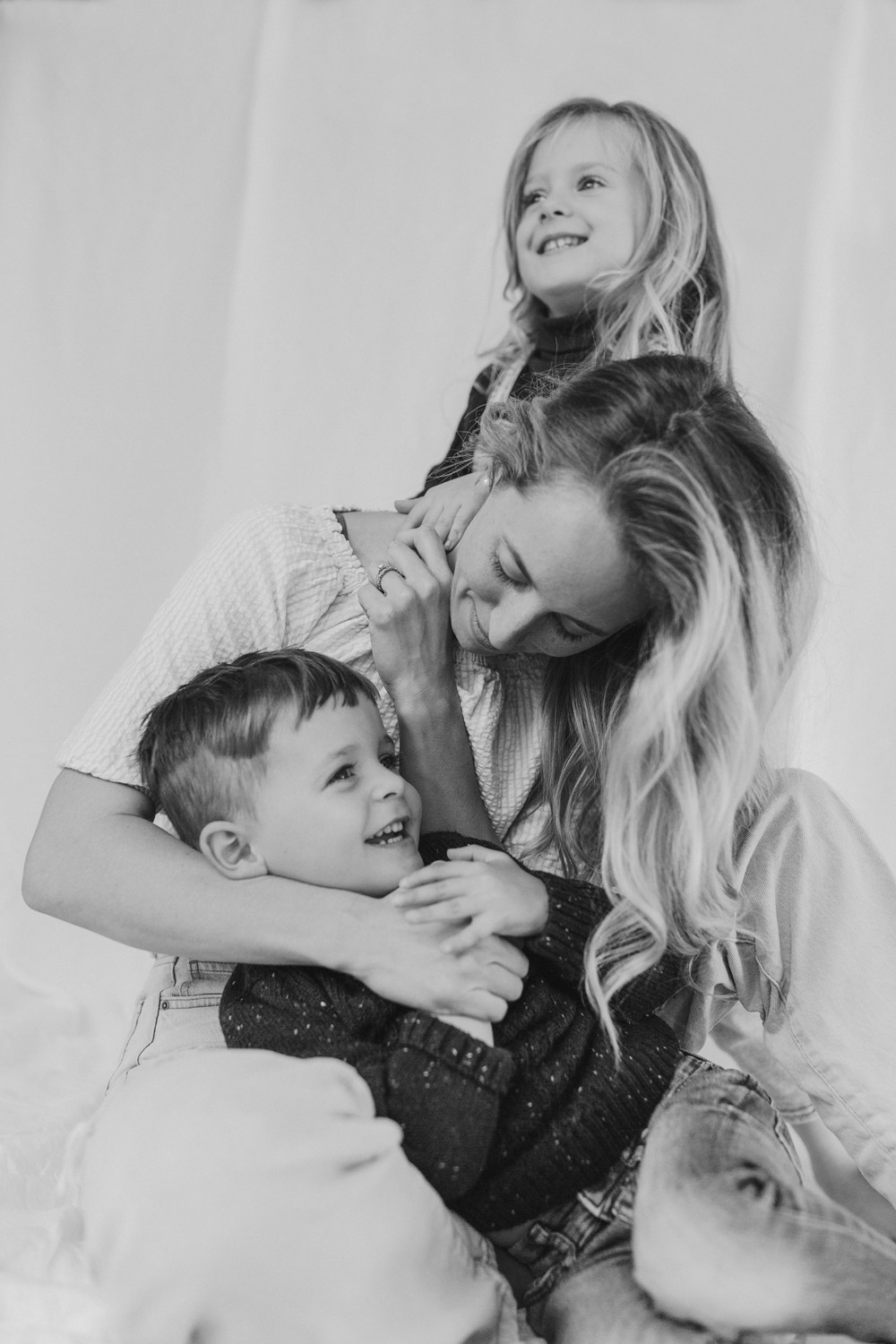 Mum and her two young kids against a white linen backdrop