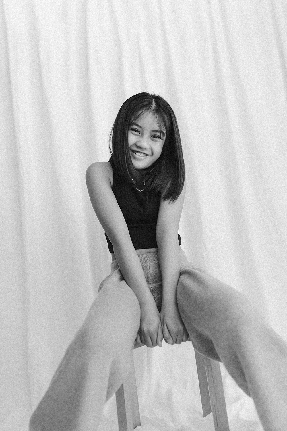 Young girl posing for a portrait in front of a white linen backdrop