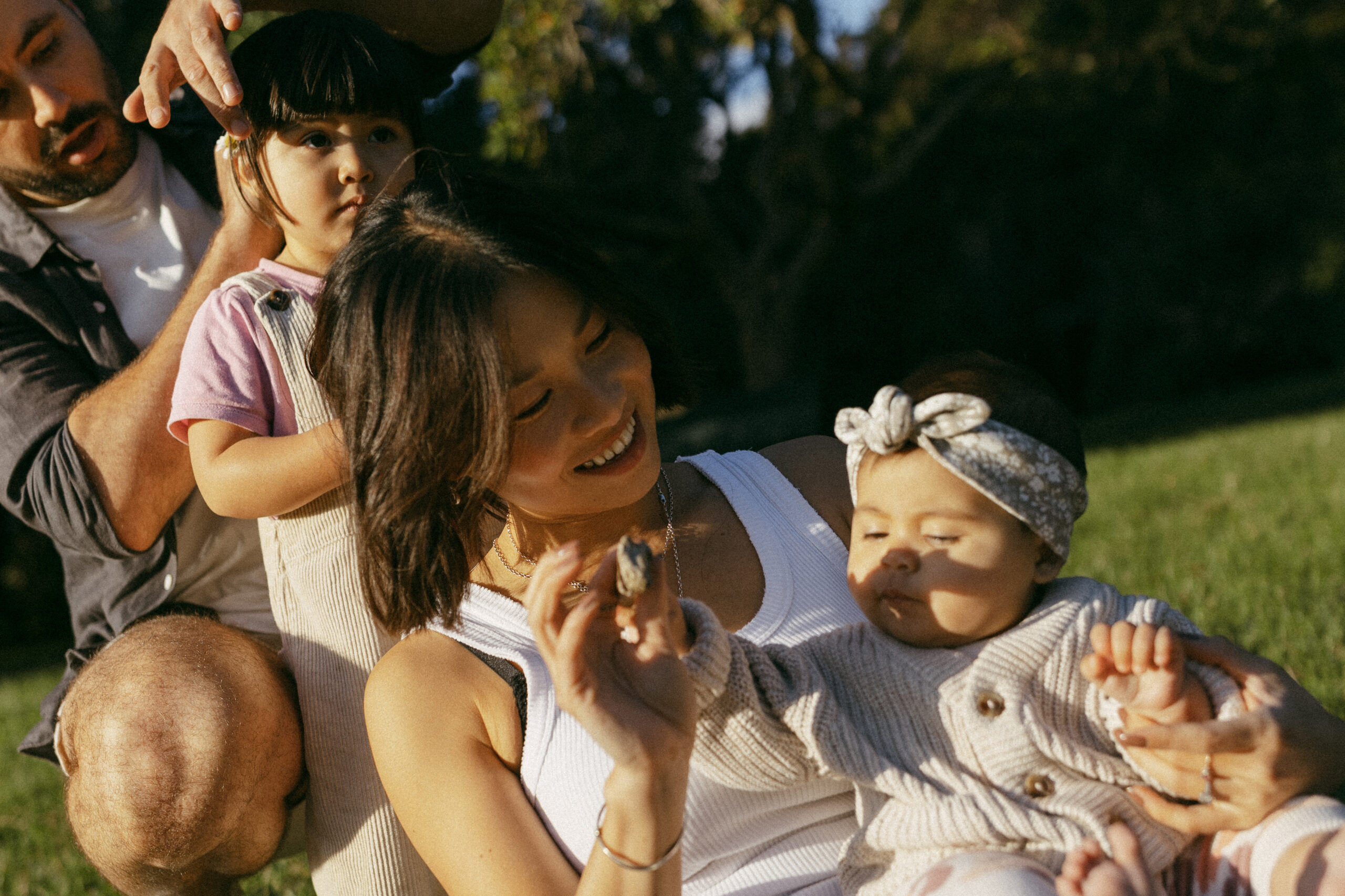 Young family sitting in sun doing each others hair